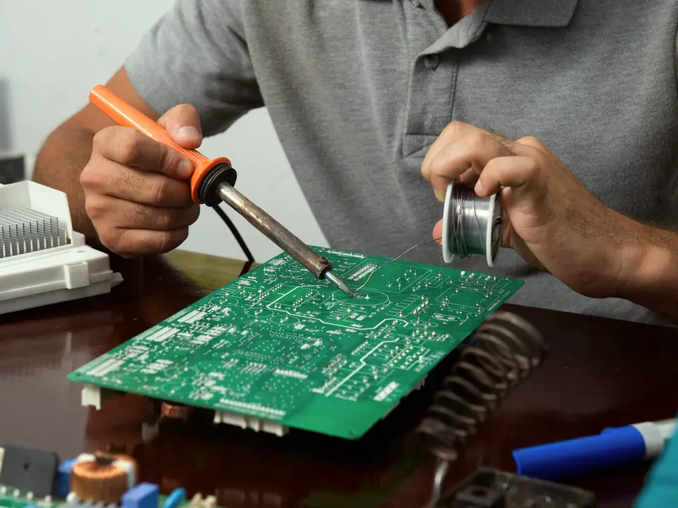 Teknik serviste tamir tezgâhında elektronik kartı havya ve lehim teliyle onaran usta